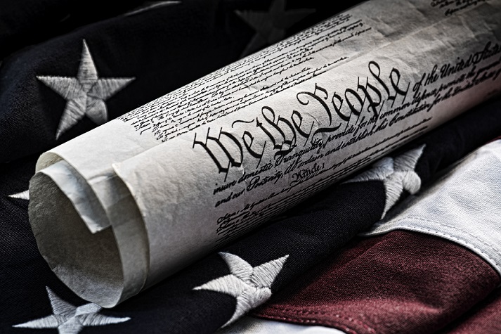 Constitution reading We the People with an American flag in the background